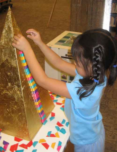 Girl playing with Golden pyramid module at the BuildIT! exhibit about architecture for kids