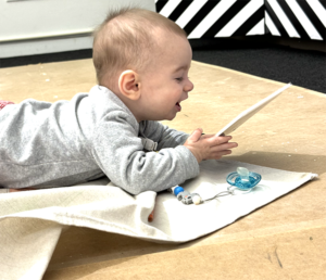 baby on his belly playing with building tools